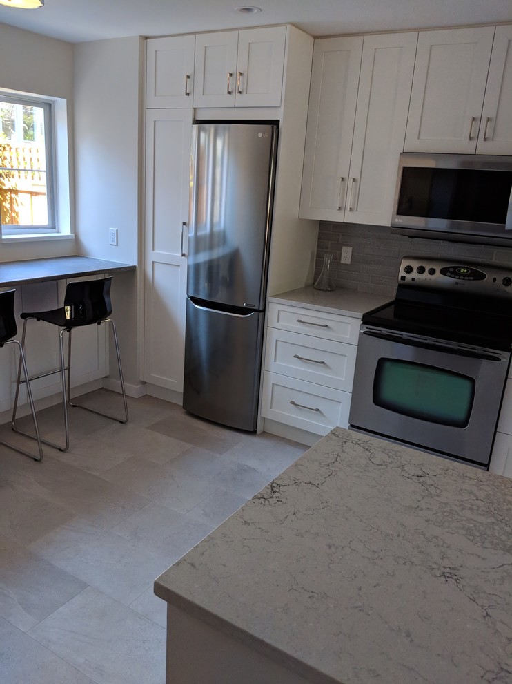 Small transitional u-shaped vinyl floor and beige floor eat-in kitchen photo in Vancouver with a single-bowl sink, shaker cabinets, white cabinets, quartz countertops, gray backsplash, ceramic backsplash, stainless steel appliances, no island and gray countertops