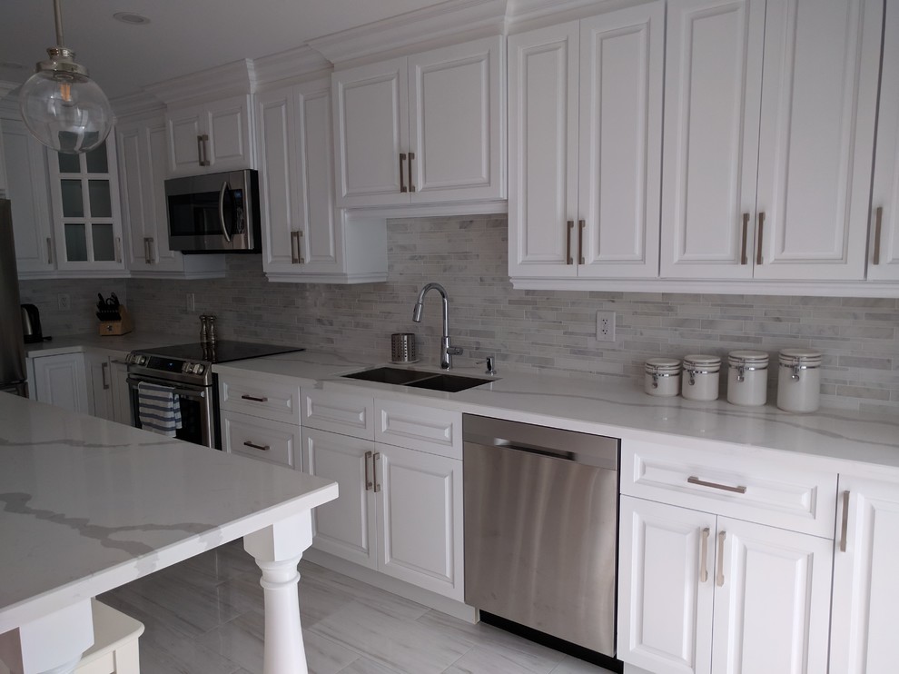 Example of a mid-sized transitional l-shaped kitchen design in Toronto with an undermount sink, raised-panel cabinets, white cabinets, stainless steel appliances and an island