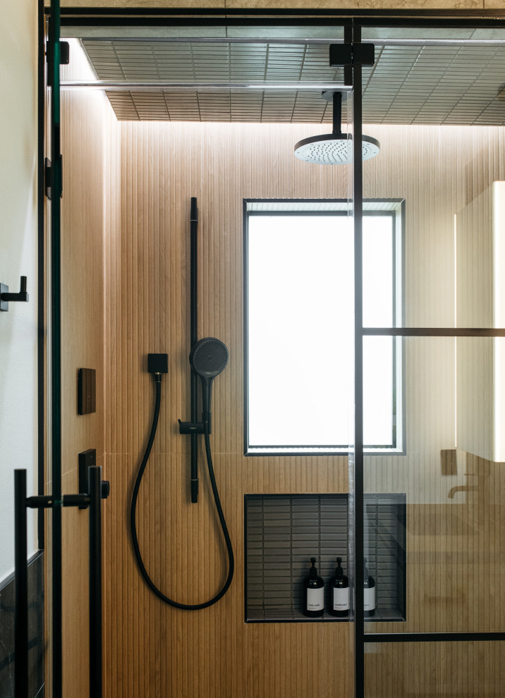 Modern inredning av ett badrum med dusch, med en dusch i en alkov, brun kakel, vita väggar och dusch med gångjärnsdörr
