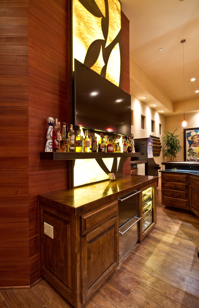 Photo of a mid-sized transitional l-shaped wet bar in Phoenix with an undermount sink, raised-panel cabinets, medium wood cabinets, copper benchtops and medium hardwood floors.