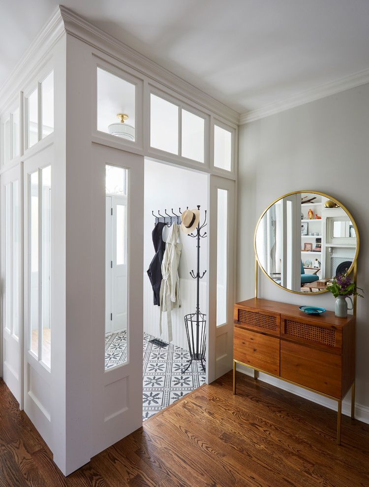 Photo of a transitional vestibule in Chicago with white walls, dark hardwood floors, a white front door and brown floor.
