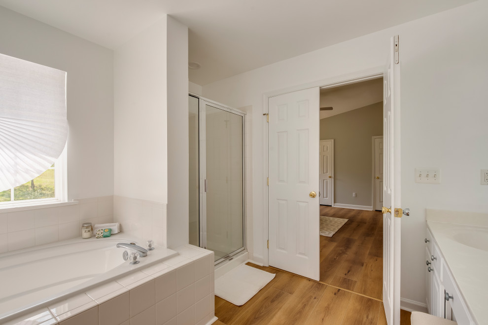 Inspiration for a large contemporary master bathroom in Baltimore with white cabinets, a corner tub, an alcove shower, vinyl floors, yellow floor, a hinged shower door, white benchtops, a built-in vanity, white walls and an integrated sink.