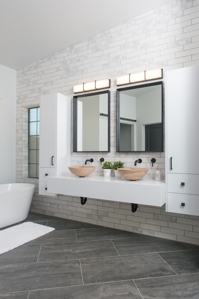 Mid-sized industrial master bathroom in Phoenix with flat-panel cabinets, white cabinets, a freestanding tub, a curbless shower, a one-piece toilet, white tile, ceramic tile, white walls, ceramic floors, a vessel sink, quartzite benchtops, grey floor, a hinged shower door and white benchtops.
