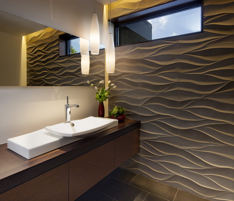 Photo of a contemporary powder room in Denver with a vessel sink, flat-panel cabinets, dark wood cabinets, wood benchtops, gray tile and brown benchtops.