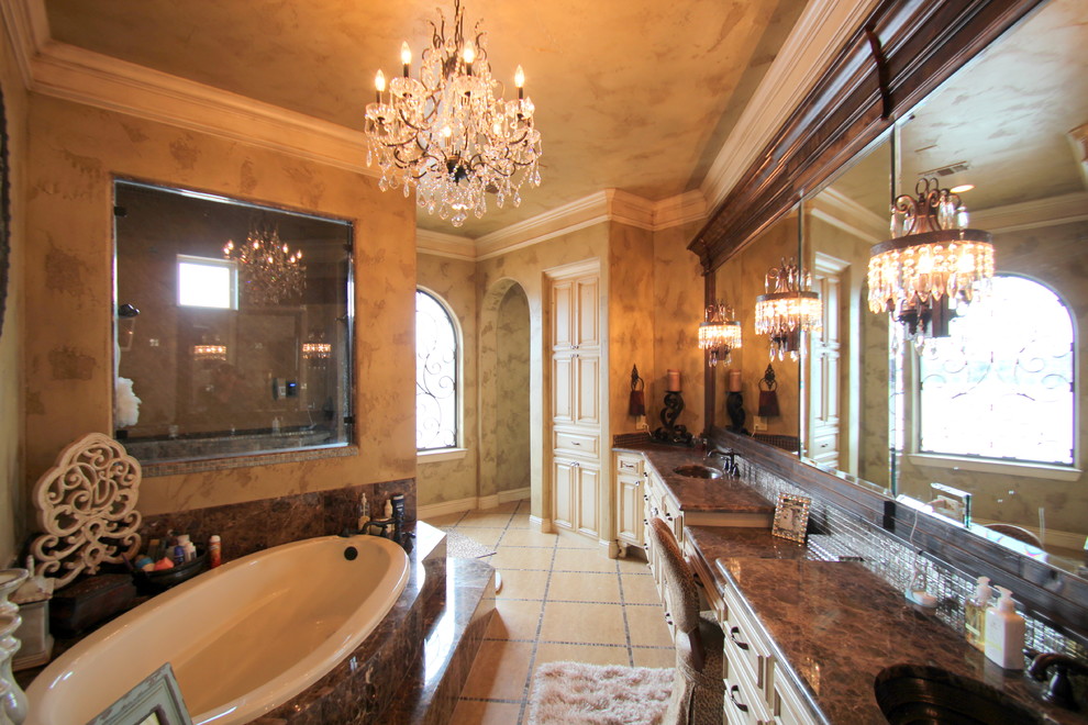 This is an example of a large traditional master bathroom in Dallas with raised-panel cabinets, beige cabinets, a drop-in tub, beige tile, black tile, porcelain tile, brown walls, porcelain floors, an undermount sink and marble benchtops.