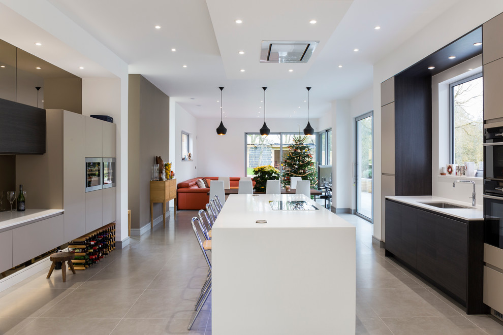 Photo of a contemporary kitchen in London with an undermount sink, flat-panel cabinets, dark wood cabinets, black appliances and with island.