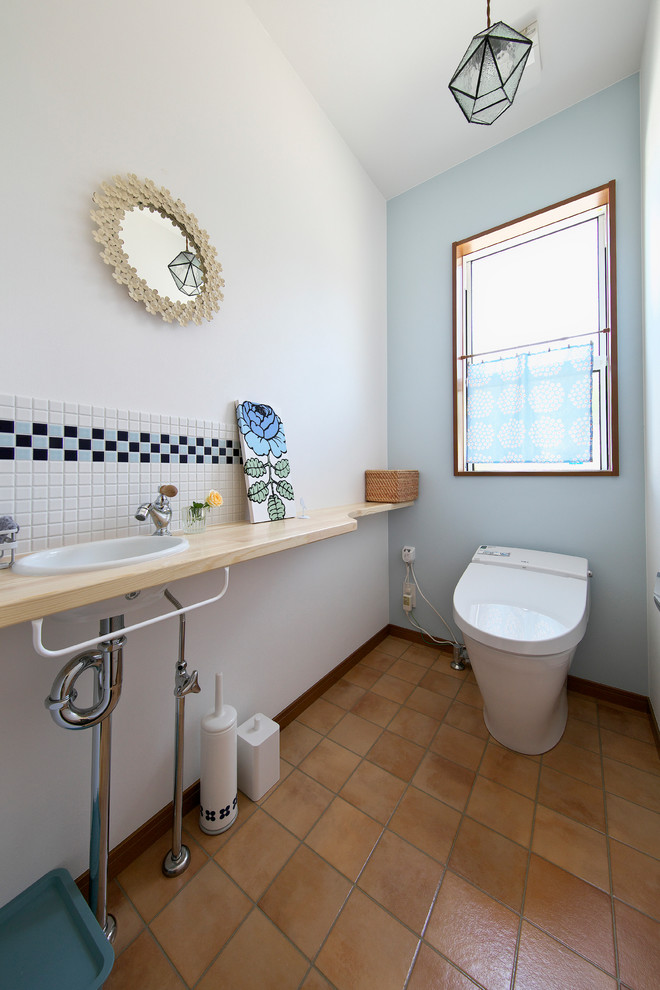 This is an example of a scandinavian powder room in Other with open cabinets, blue tile and tile benchtops.