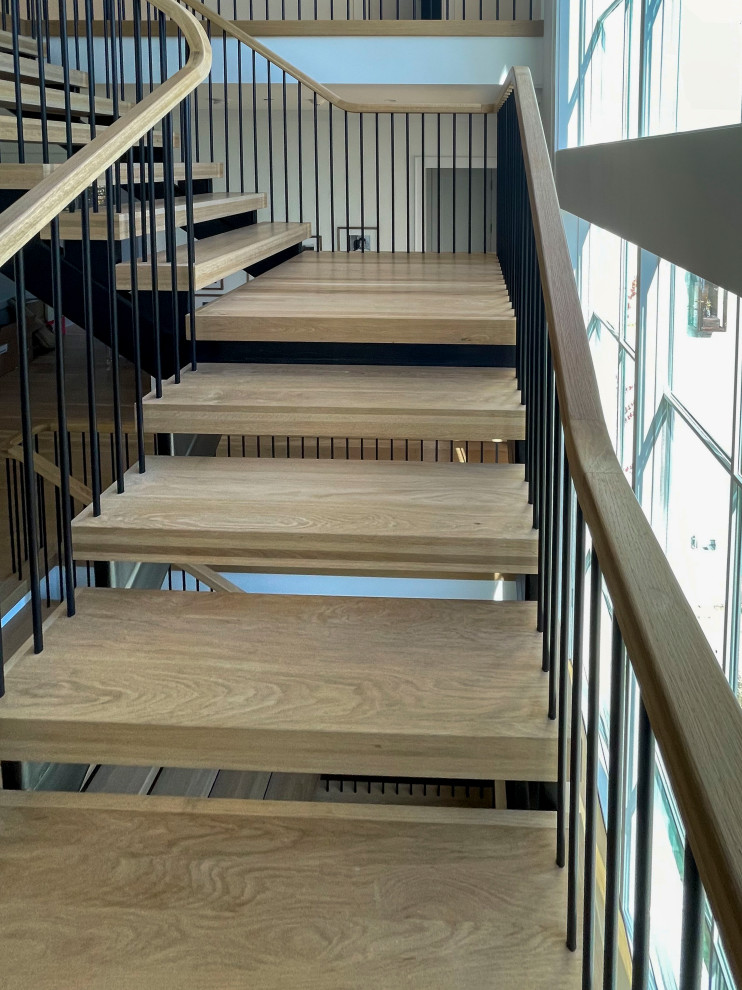 Свежая идея для дизайна: огромная лестница на больцах в стиле модернизм с деревянными ступенями, перилами из смешанных материалов и стенами из вагонки - отличное фото интерьера