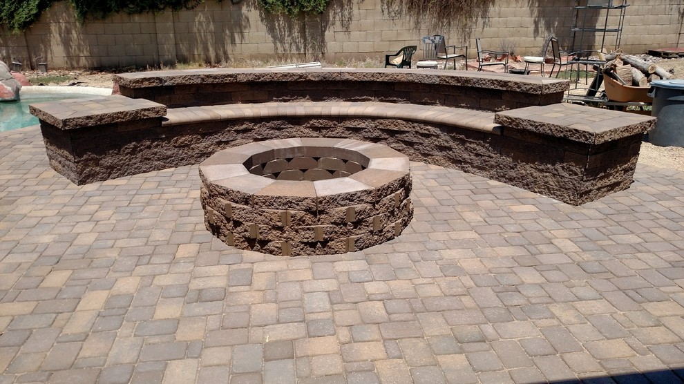 This is an example of a mid-sized traditional backyard full sun xeriscape in Other with natural stone pavers and a fire feature.