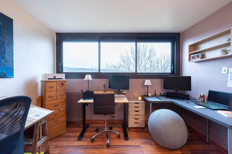 Inspiration för mellanstora moderna hemmabibliotek, med lila väggar, mellanmörkt trägolv, ett fristående skrivbord och brunt golv