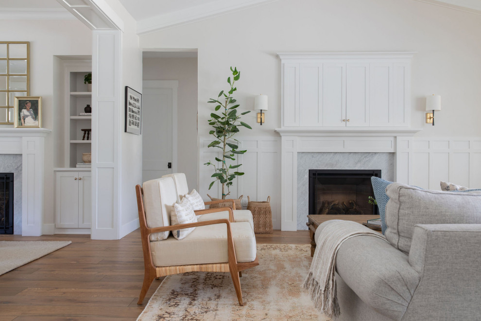 Photo of a large traditional open concept living room in Sacramento with white walls, medium hardwood floors, a standard fireplace, a wood fireplace surround, a built-in media wall, brown floor, vaulted and decorative wall panelling.