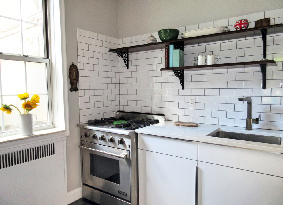 Photo of a small country galley separate kitchen in New York with a drop-in sink, flat-panel cabinets, white cabinets, quartz benchtops, white splashback, subway tile splashback, white appliances, vinyl floors and no island.