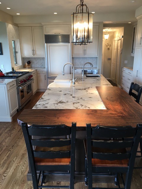 Kitchen - mid-sized transitional u-shaped medium tone wood floor kitchen idea in Denver with raised-panel cabinets, white cabinets, marble countertops, an island, a farmhouse sink, white backsplash, stone tile backsplash and paneled appliances