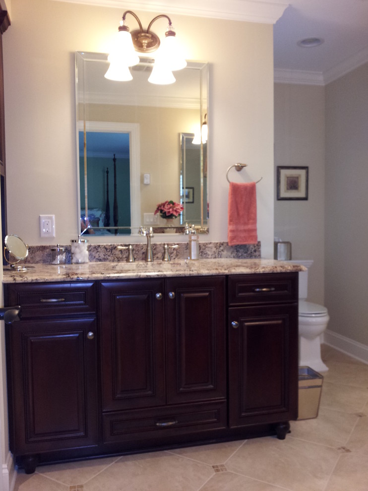 Photo of a large traditional master bathroom in Other with an undermount sink, raised-panel cabinets, dark wood cabinets, granite benchtops, an alcove shower, a two-piece toilet, beige tile, ceramic tile, beige walls and porcelain floors.