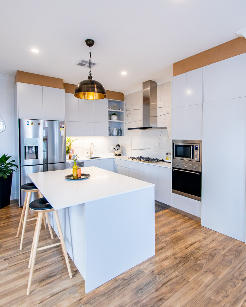 Photo of a large contemporary l-shaped eat-in kitchen in Sydney with an undermount sink, grey cabinets, quartz benchtops, white splashback, marble splashback, stainless steel appliances, bamboo floors, with island and white benchtop.