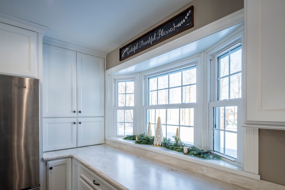 Inspiration for a large transitional l-shaped eat-in kitchen remodel with an undermount sink, recessed-panel cabinets, white cabinets, solid surface countertops, gray backsplash, stainless steel appliances and an island