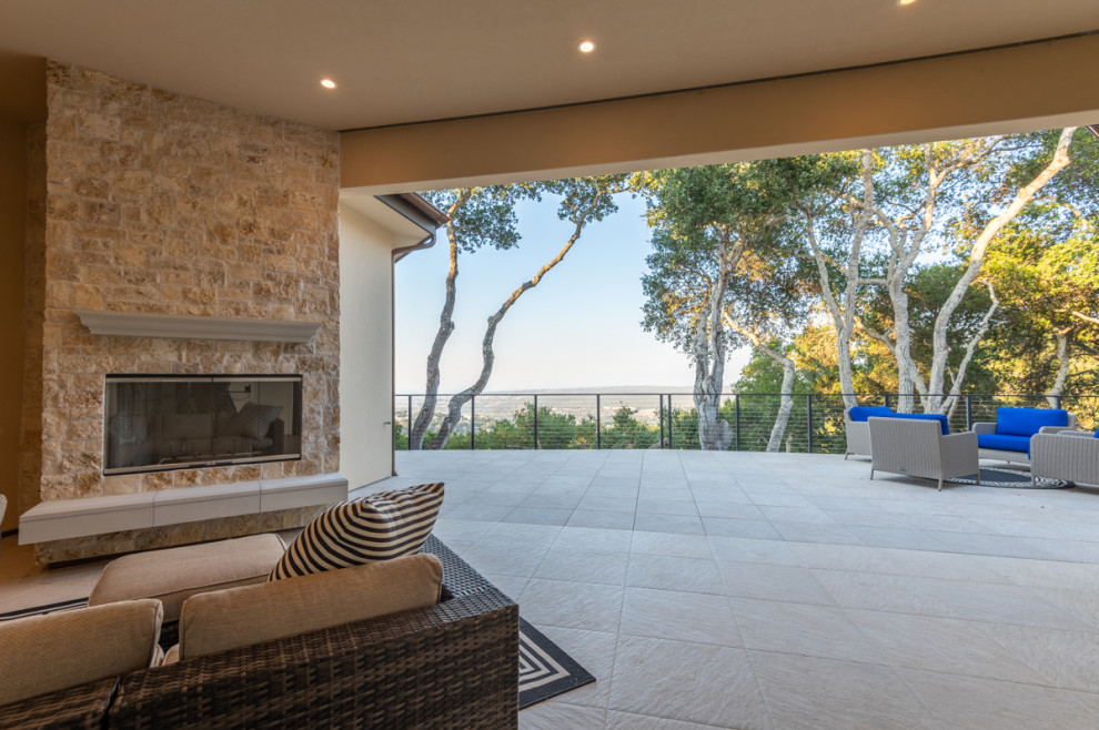 Photo of an expansive back patio in Other with a fireplace, tiled flooring and a roof extension.
