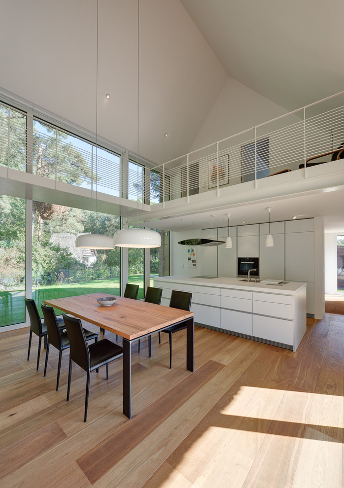 Große Moderne Wohnküche mit weißer Wandfarbe und hellem Holzboden in Berlin