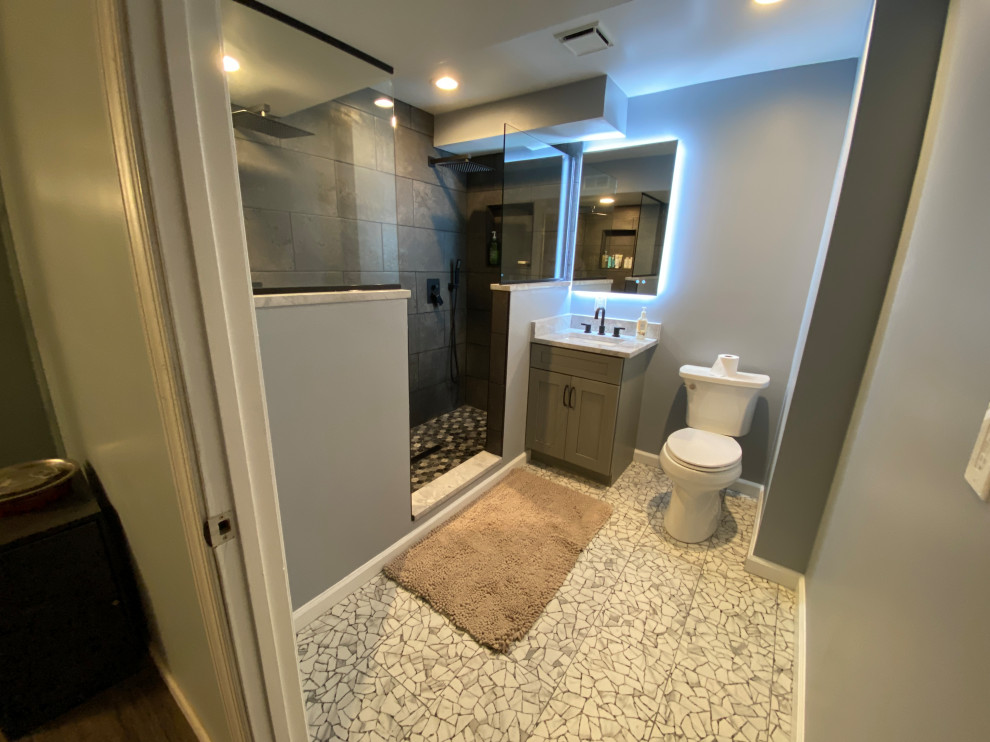 Пример оригинального дизайна: ванная комната среднего размера в стиле модернизм с фасадами в стиле шейкер, серыми фасадами, двойным душем, раздельным унитазом, серой плиткой, серыми стенами, душевой кабиной, врезной раковиной, столешницей из искусственного кварца, открытым душем, тумбой под одну раковину и напольной тумбой