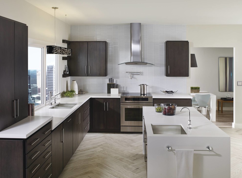 Photo of a large modern l-shaped eat-in kitchen in Cleveland with an undermount sink, flat-panel cabinets, dark wood cabinets, quartz benchtops, white splashback, porcelain splashback, stainless steel appliances, light hardwood floors and with island.