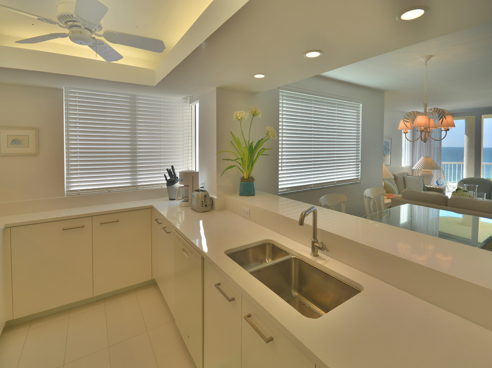 Inspiration for a small beach style u-shaped eat-in kitchen in Miami with a double-bowl sink, flat-panel cabinets, white cabinets, quartzite benchtops, white splashback, white appliances, ceramic floors, no island and white floor.