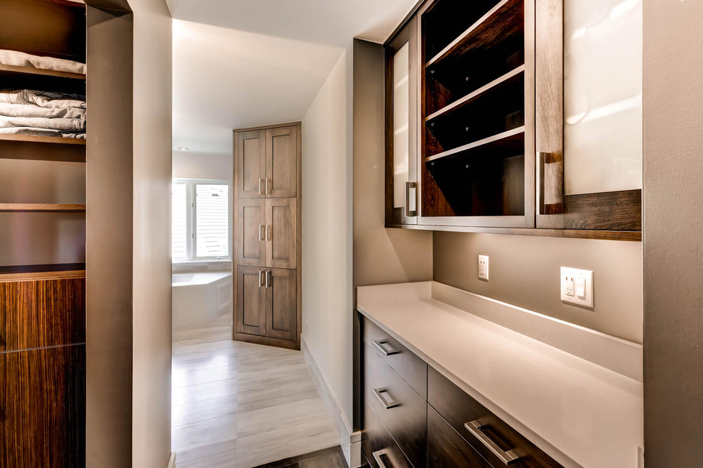 Large transitional gender-neutral walk-in wardrobe in Denver with shaker cabinets, dark wood cabinets and ceramic floors.