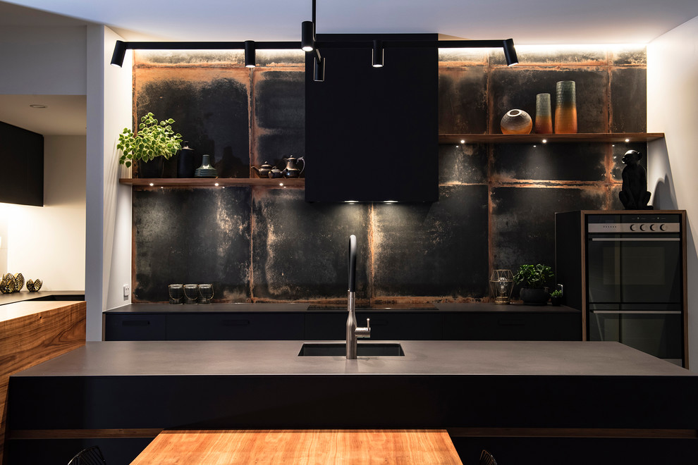 Large modern single-wall eat-in kitchen in Other with a drop-in sink, flat-panel cabinets, black cabinets, metallic splashback, black appliances, with island and black benchtop.