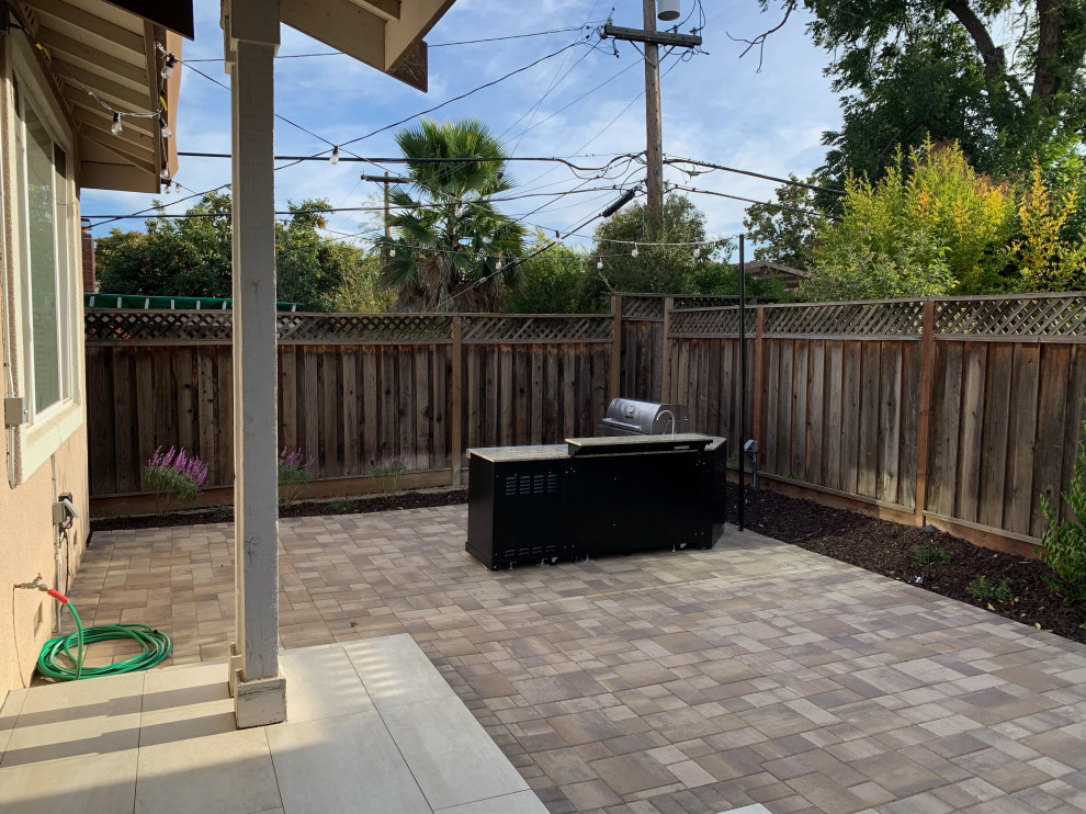 This is an example of a mid-sized arts and crafts backyard partial sun formal garden for summer in San Francisco with a water feature, concrete pavers and a wood fence.