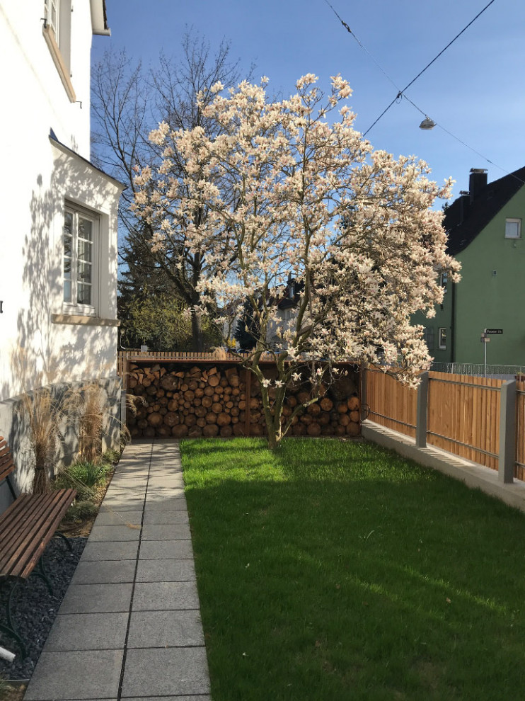 Idee per un giardino formale country esposto in pieno sole davanti casa in primavera con un ingresso o sentiero, pavimentazioni in pietra naturale e recinzione in legno