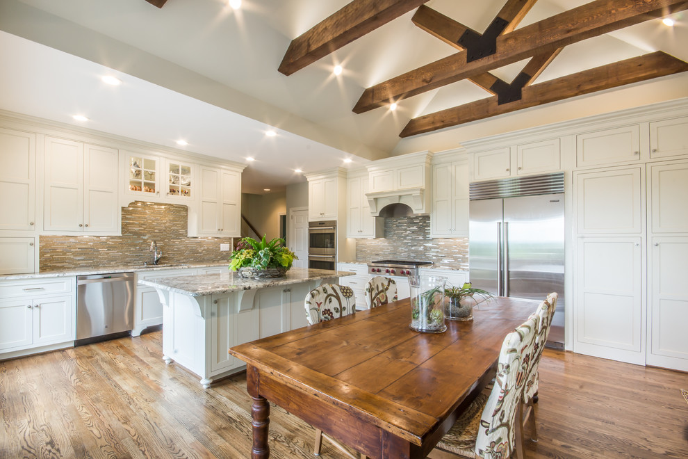 Huge transitional l-shaped medium tone wood floor eat-in kitchen photo in Birmingham with an undermount sink, recessed-panel cabinets, white cabinets, granite countertops, multicolored backsplash, glass tile backsplash, stainless steel appliances and an island