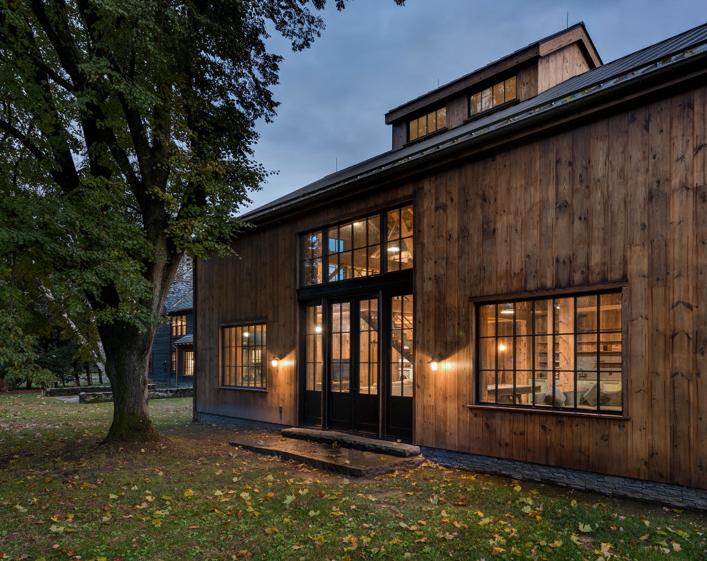 Imagen de fachada de casa campestre grande de dos plantas con revestimiento de madera y panel y listón