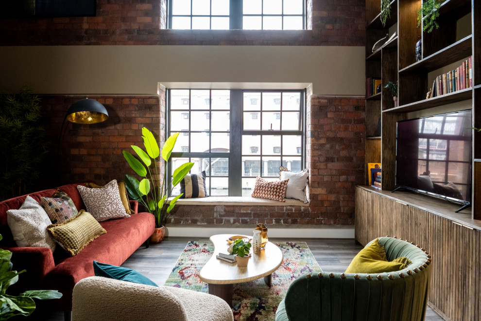 Large eclectic open concept living room in Manchester with beige walls, laminate floors, a built-in media wall, brown floor and exposed beam.
