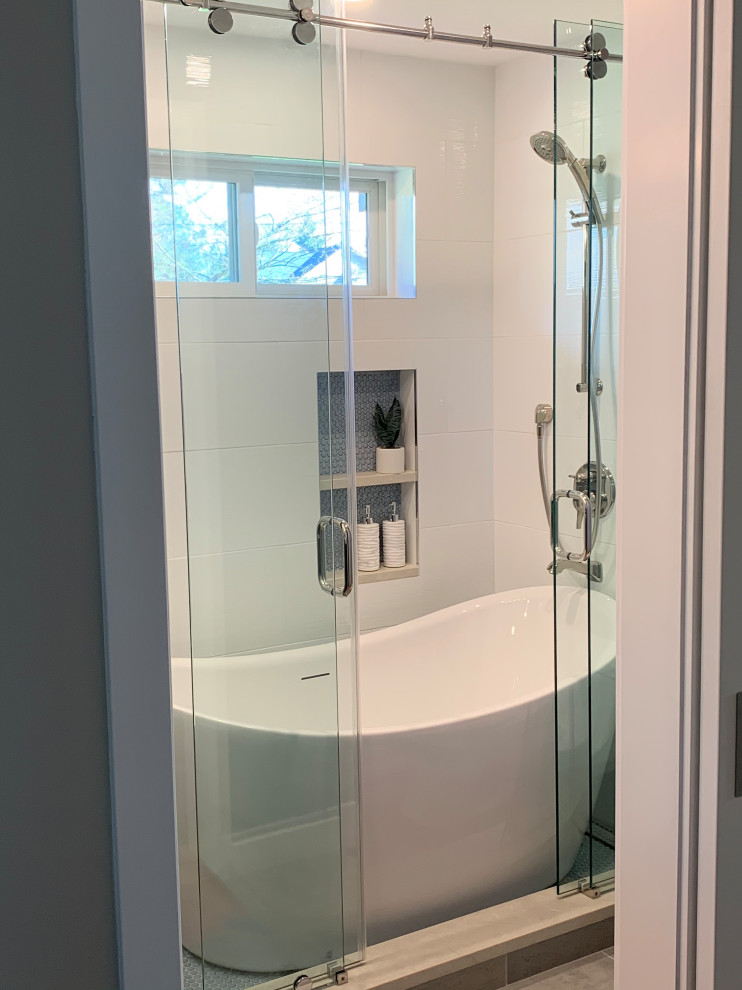 Inspiration for a medium sized modern ensuite wet room bathroom with flat-panel cabinets, black cabinets, a freestanding bath, white tiles, porcelain tiles, grey walls, porcelain flooring, a submerged sink, engineered stone worktops, grey floors, a sliding door, white worktops, a wall niche, double sinks and a floating vanity unit.