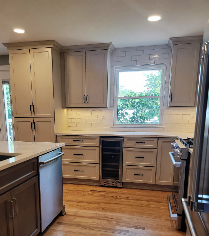 Inspiration for a mid-sized transitional l-shaped medium tone wood floor and yellow floor eat-in kitchen remodel with an undermount sink, flat-panel cabinets, gray cabinets, quartz countertops, white backsplash, ceramic backsplash, stainless steel appliances, an island and white countertops
