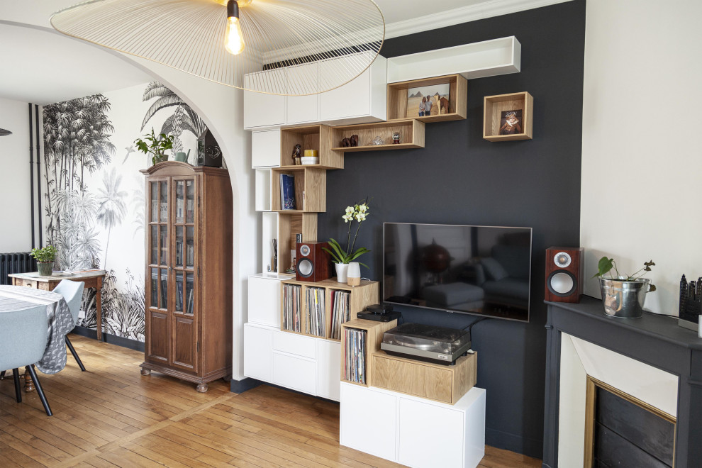 Aménagement d'une salle de séjour éclectique avec un mur noir, un sol en bois brun, un téléviseur fixé au mur et un sol marron.