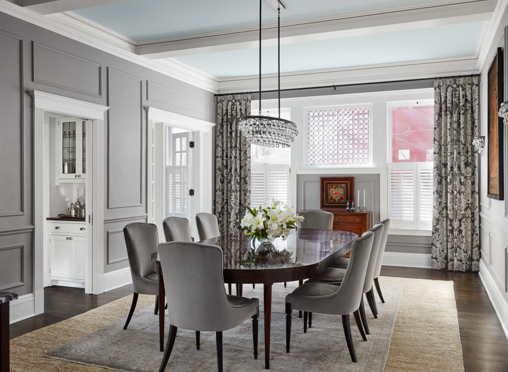 This is an example of a transitional separate dining room in Chicago with grey walls, medium hardwood floors, no fireplace, brown floor, exposed beam and panelled walls.