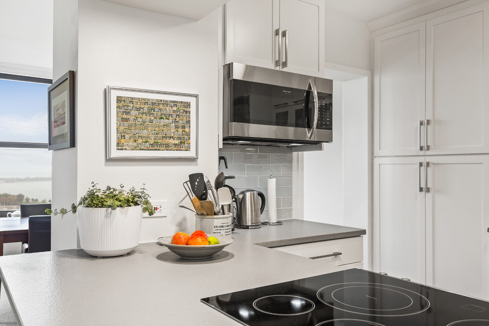 Eat-in kitchen - mid-sized transitional l-shaped brown floor eat-in kitchen idea in Chicago with an undermount sink, shaker cabinets, white cabinets, quartz countertops, green backsplash, ceramic backsplash, stainless steel appliances, an island and gray countertops