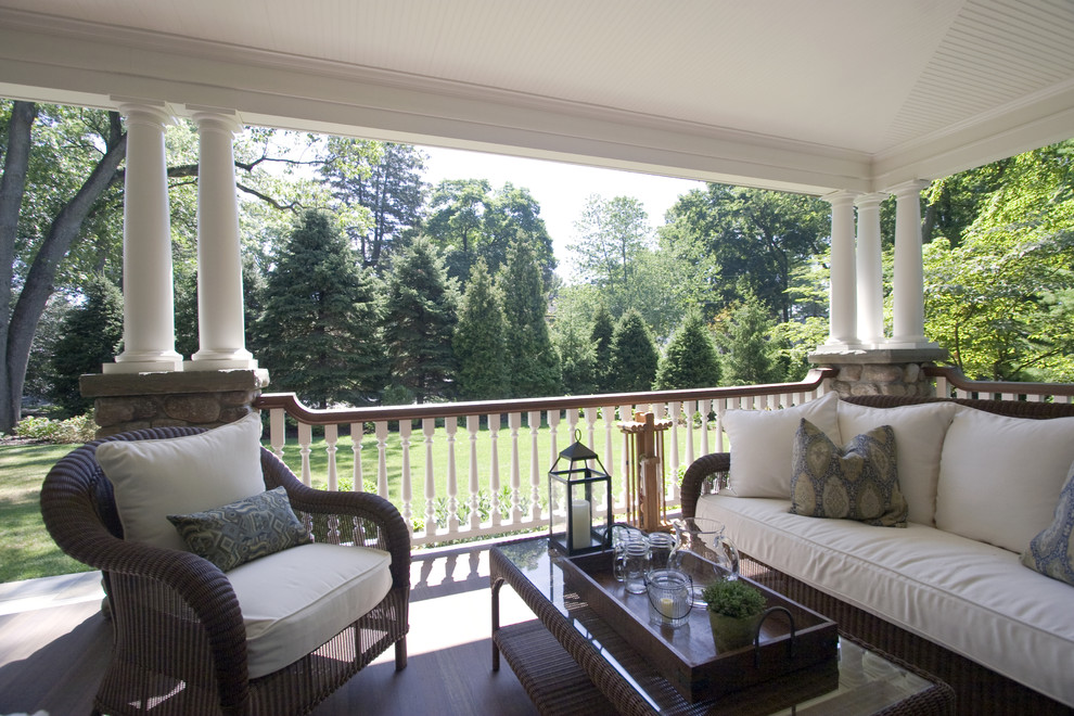 This is an example of a large traditional front yard verandah in New York with a roof extension and decking.