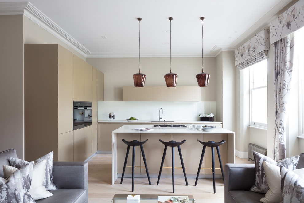 Mid-sized contemporary l-shaped open plan kitchen in Other with flat-panel cabinets, brown cabinets, white splashback, glass sheet splashback, light hardwood floors, with island, beige floor and white benchtop.