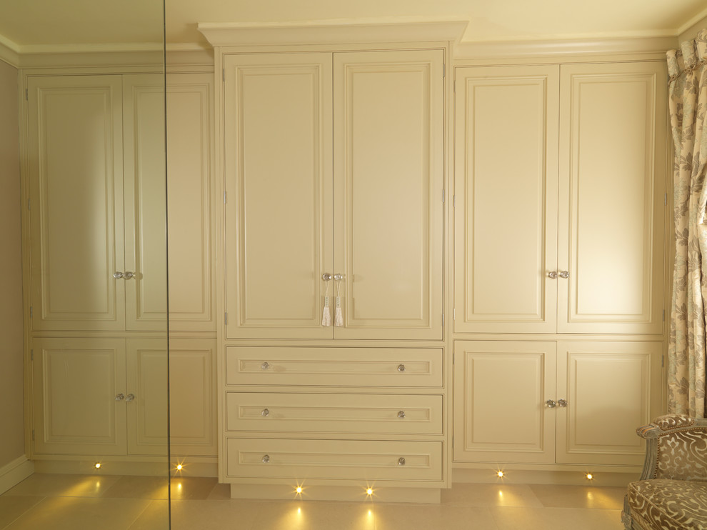 Photo of a large contemporary gender-neutral storage and wardrobe in Other with raised-panel cabinets, green cabinets and limestone floors.