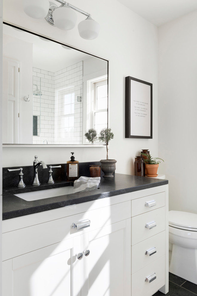 Country bathroom in Minneapolis with beaded inset cabinets, white cabinets, white walls and black benchtops.