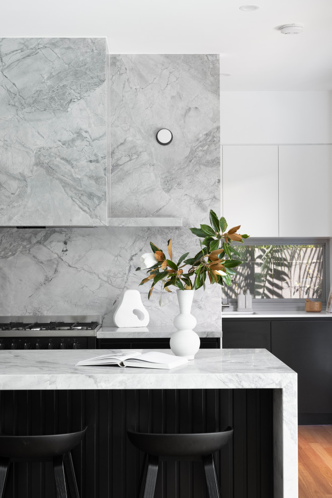 Modern inredning av ett stort grå grått kök och matrum, med en undermonterad diskho, svarta skåp, marmorbänkskiva, grått stänkskydd, stänkskydd i marmor, svarta vitvaror, mellanmörkt trägolv, en köksö och brunt golv