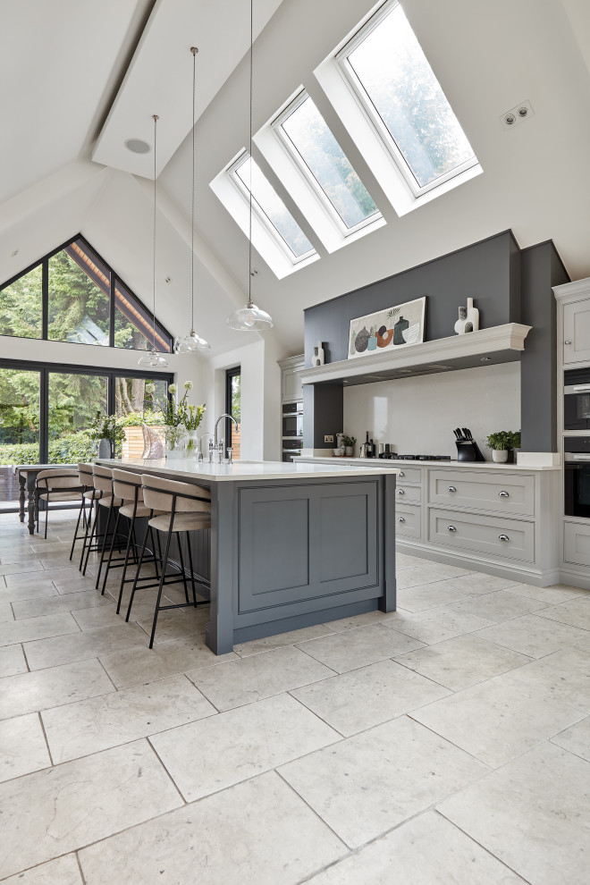 This is an example of a large contemporary galley open plan kitchen in Manchester with a built-in sink, shaker cabinets, grey cabinets, quartz worktops, white splashback, engineered quartz splashback, stainless steel appliances, an island and white worktops.