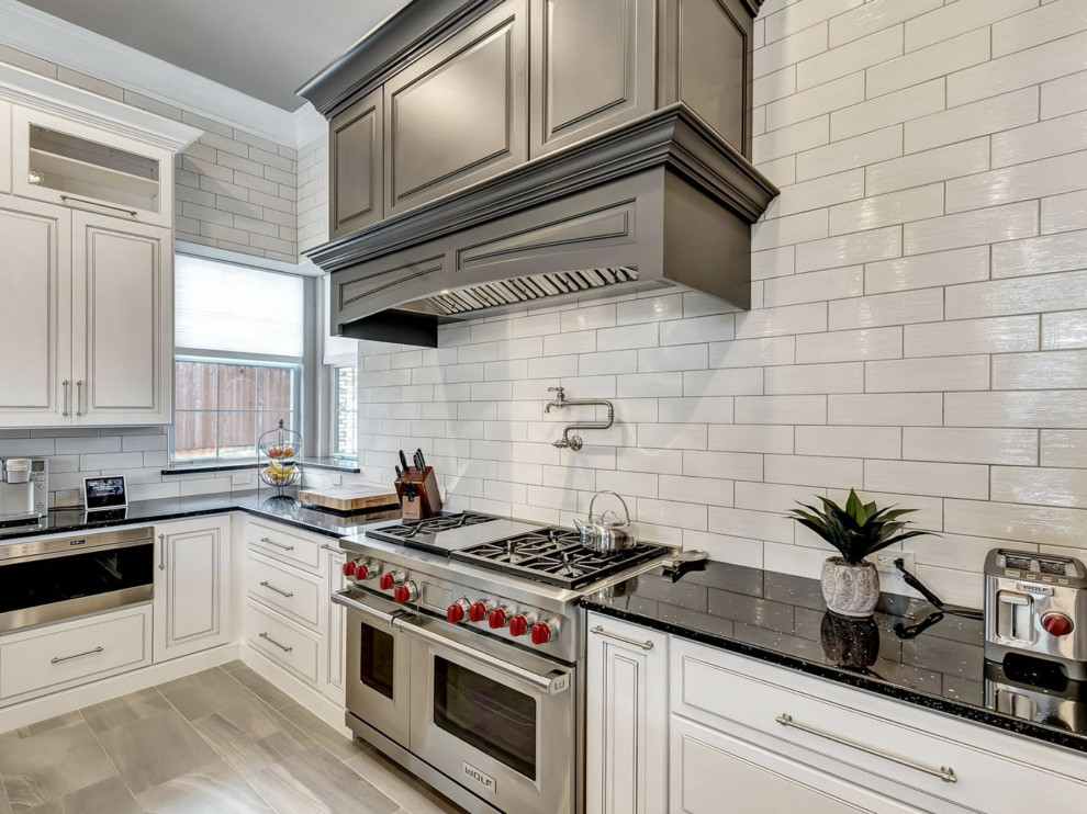 Inspiration for a mid-sized transitional l-shaped travertine floor and gray floor eat-in kitchen remodel in Atlanta with a drop-in sink, beaded inset cabinets, beige cabinets, granite countertops, white backsplash, subway tile backsplash, stainless steel appliances, an island and black countertops