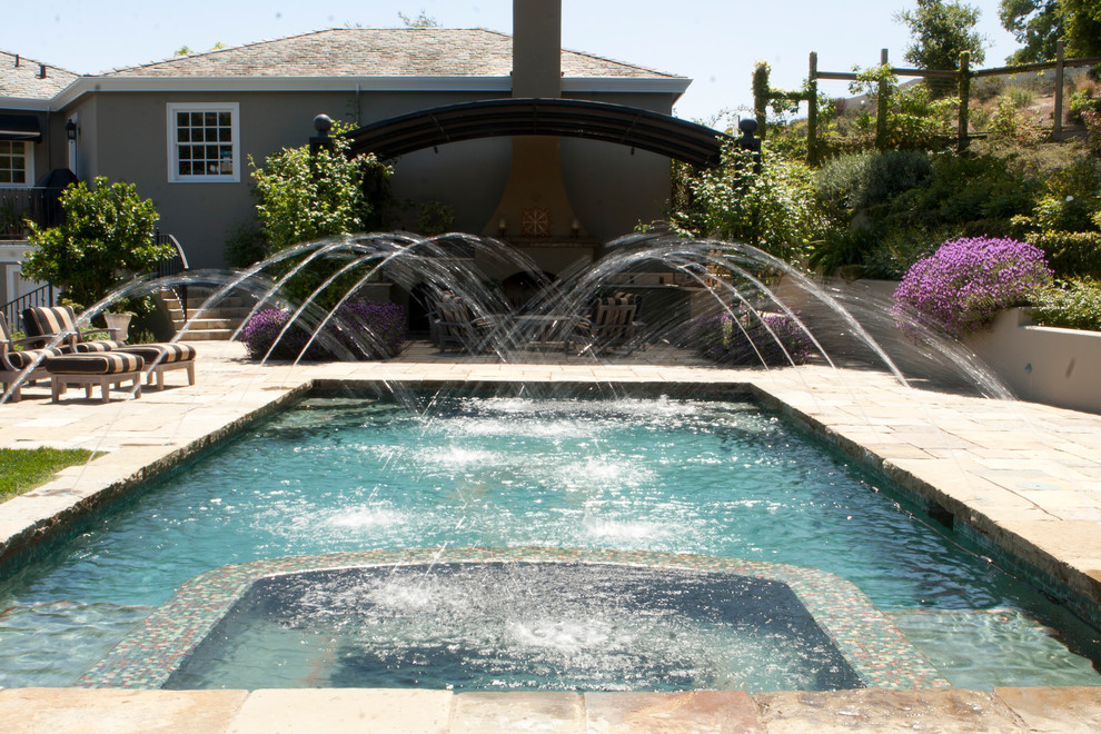Large traditional backyard rectangular lap pool in San Francisco with a water feature and natural stone pavers.
