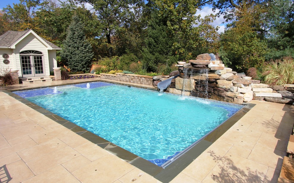 Design ideas for a mid-sized traditional backyard rectangular pool in Chicago with a water slide and concrete pavers.