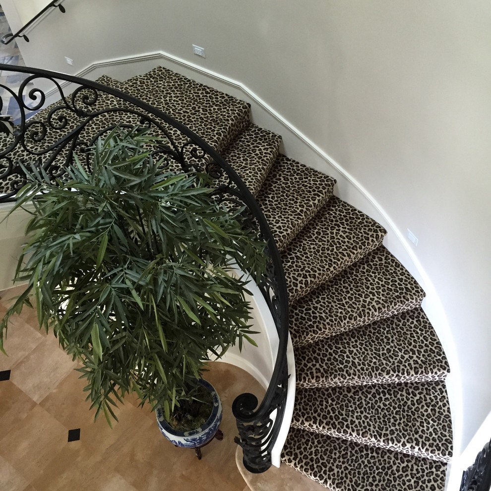 This is an example of a large traditional carpeted curved staircase in Orange County with carpet risers.