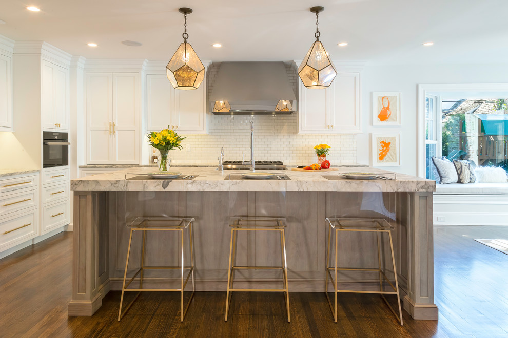 Inspiration for an expansive transitional l-shaped eat-in kitchen in New York with a farmhouse sink, beaded inset cabinets, white cabinets, quartzite benchtops, white splashback, porcelain splashback, stainless steel appliances, medium hardwood floors, with island, brown floor and grey benchtop.