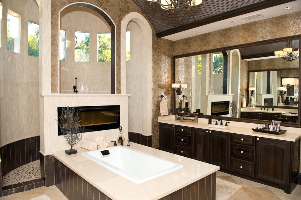 Expansive modern master bathroom in Phoenix with an undermount sink, raised-panel cabinets, dark wood cabinets, marble benchtops, a drop-in tub, an open shower, beige tile, beige walls and travertine floors.