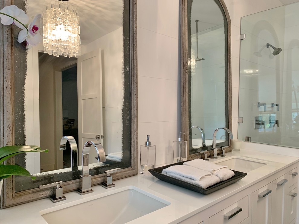 This is an example of a large modern master bathroom in Houston with a one-piece toilet, white tile, subway tile, white walls, grey floor, a hinged shower door, white benchtops, shaker cabinets, white cabinets, a double shower, porcelain floors, an undermount sink, glass benchtops, an enclosed toilet, a double vanity, a built-in vanity and an undermount tub.